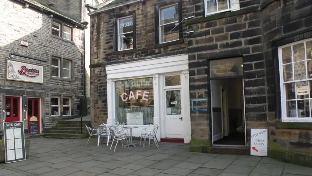 Façade accueillante d'un café de quartier avec des chaises installées sur une rue pavée.