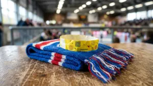 Une écharpe bleue, rouge et blanche posée avec un bracelet en papier jaune marqué.