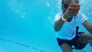 Un jeune garçon sous l'eau fait un signe de pouce levé dans la piscine.