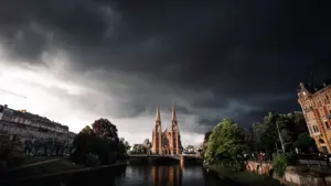 Ciel orageux menaçant au-dessus d'une église près d'une rivière en France.