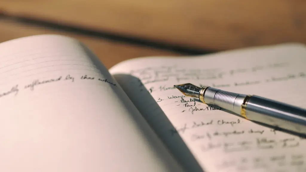 Un stylo plume posé sur un journal manuscrit, évoquant l'écriture d'un roman.