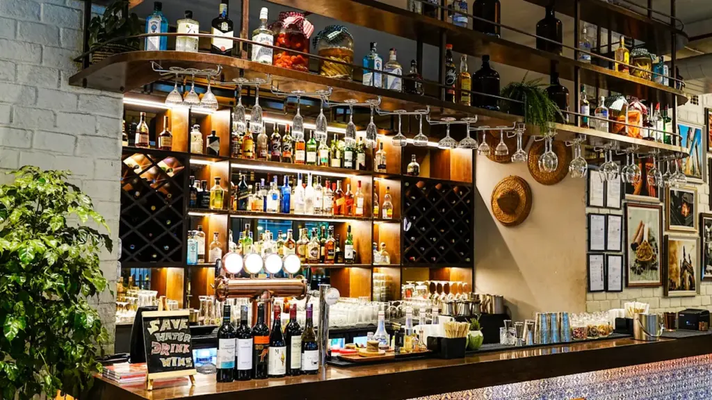 Un bar bien approvisionné avec des bouteilles et des verres suspendus au comptoir.