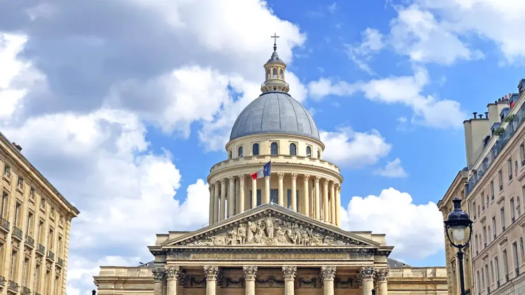 Le dôme majestueux du Panthéon à Paris sous un ciel bleu parsemé de nuages.