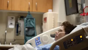 Patient alité dans une chambre d'hôpital après une intervention chirurgicale médicale.
