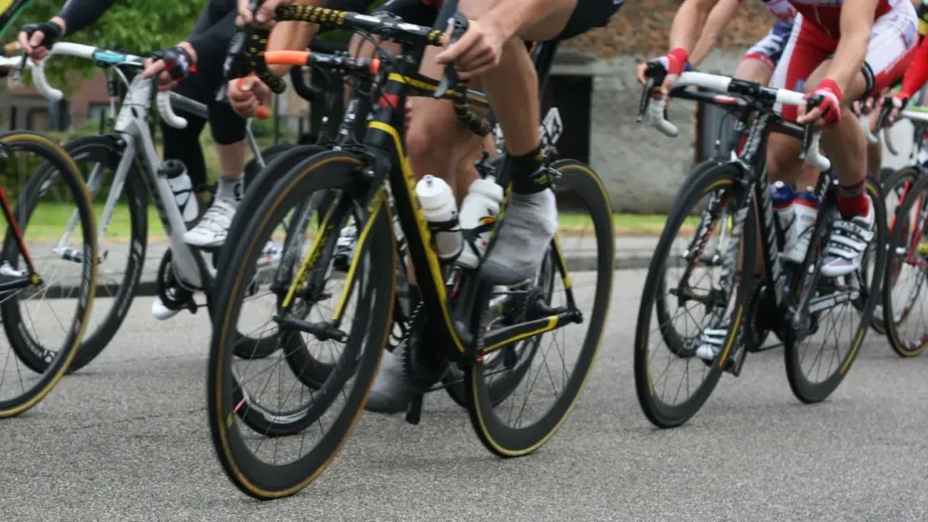Plusieurs cyclistes en tenue professionnelle roulent en groupe serré sur une route goudronnée.