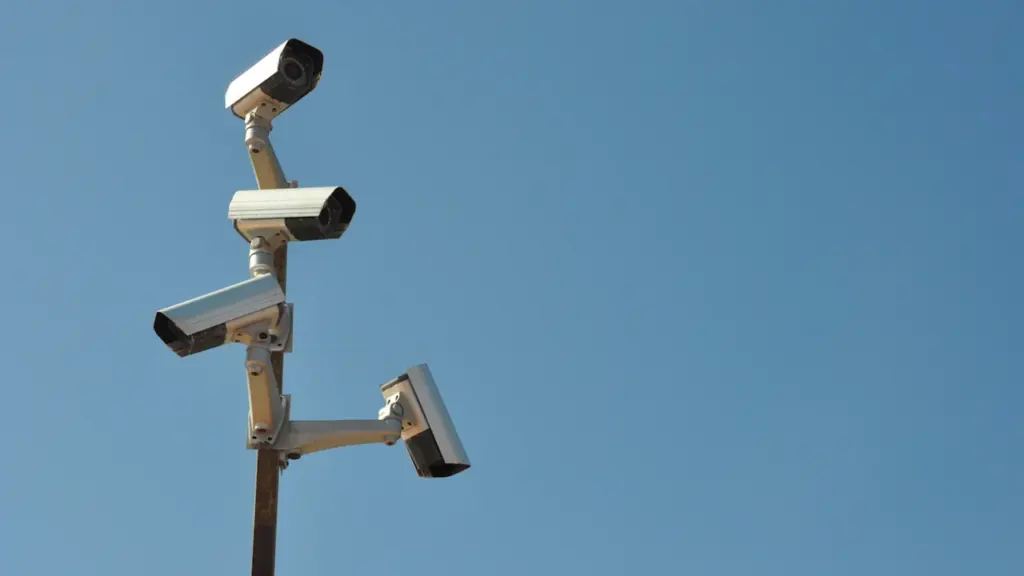 Plusieurs caméras de surveillance fixées sur un mât sous un ciel bleu dégagé.