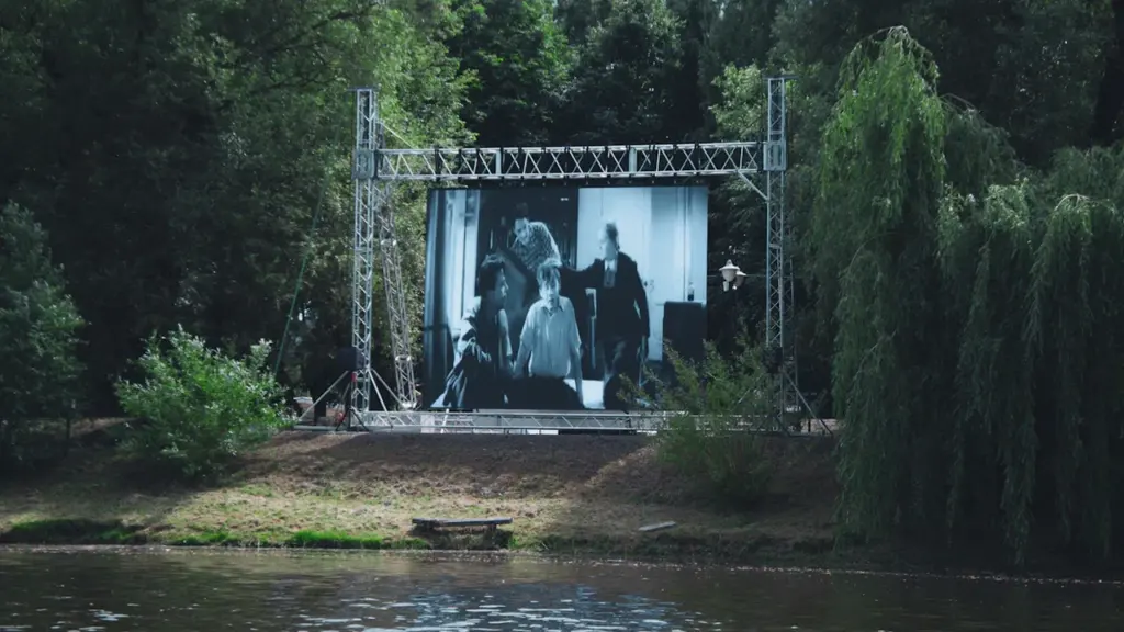 Un grand écran de cinéma installé en plein air au bord de l'eau.