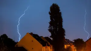 Foudre frappant au-dessus de maisons résidentielles lors d'un violent orage nocturne.