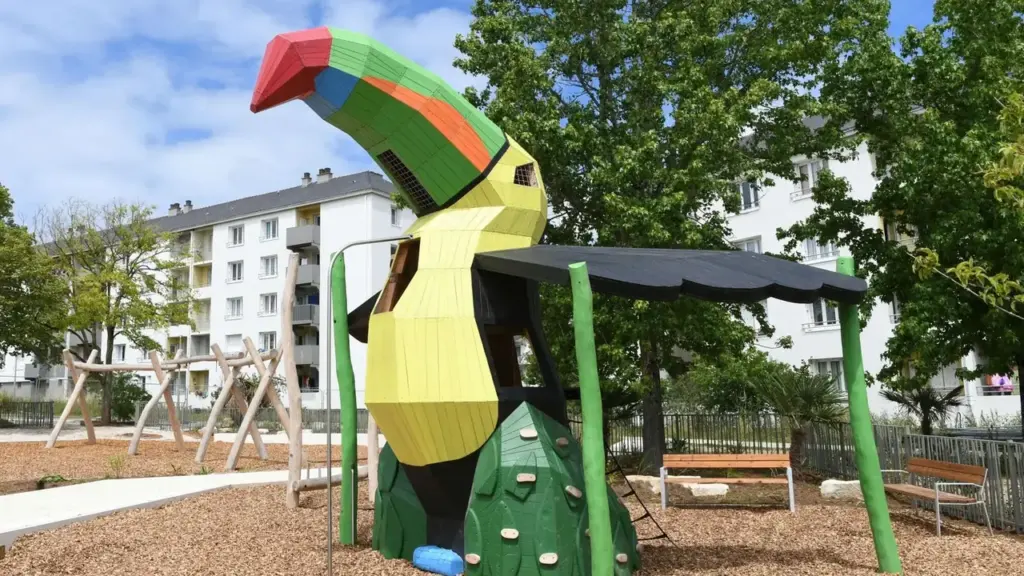 Une structure de jeu pour enfants en forme de toucan multicolore dans un parc urbain.