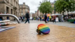 Un badge rond aux couleurs de l'arc-en-ciel posé sur une table en bois extérieure.