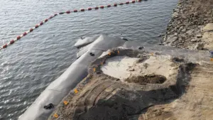 Chantier de travaux publics avec barrière de protection sur un bord de rive.
