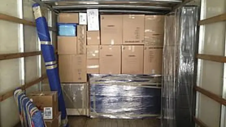Intérieur d'un camion de déménagement rempli de cartons et d'objets emballés.
