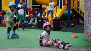 Jeunes enfants apprenant le roller avec des protections sur une aire de jeux.