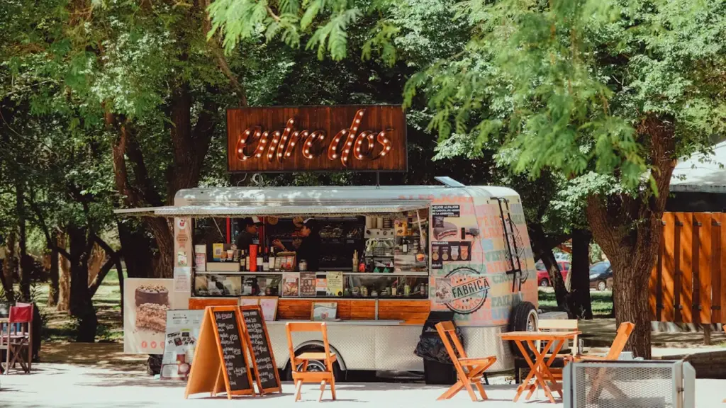 Un foodtruck stationné sous des arbres en ville, invitant à la convivialité et restauration.