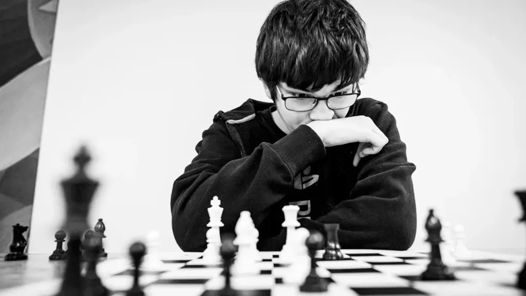Un jeune garçon concentré devant un échiquier, symbolisant la stratégie et l'avenir.