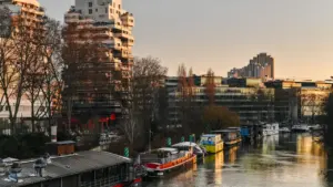 Plusieurs péniches amarrées le long d'une rivière devant des immeubles résidentiels et de bureaux.