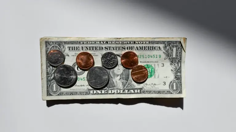 Des pièces de monnaie posées sur un billet d'un dollar américain.