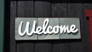 Panneau décoratif en métal avec l'inscription Welcome fixé sur un mur en bois.