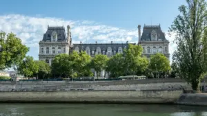 Façade majestueuse de l'Hôtel de Ville de Paris bordant la Seine sous un ciel bleu.