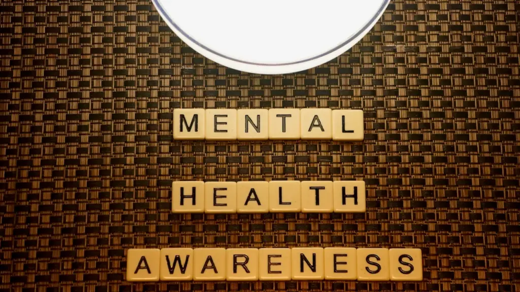 Mots 'Mental Health Awareness' formés avec des lettres de jeu sur fond texturé.