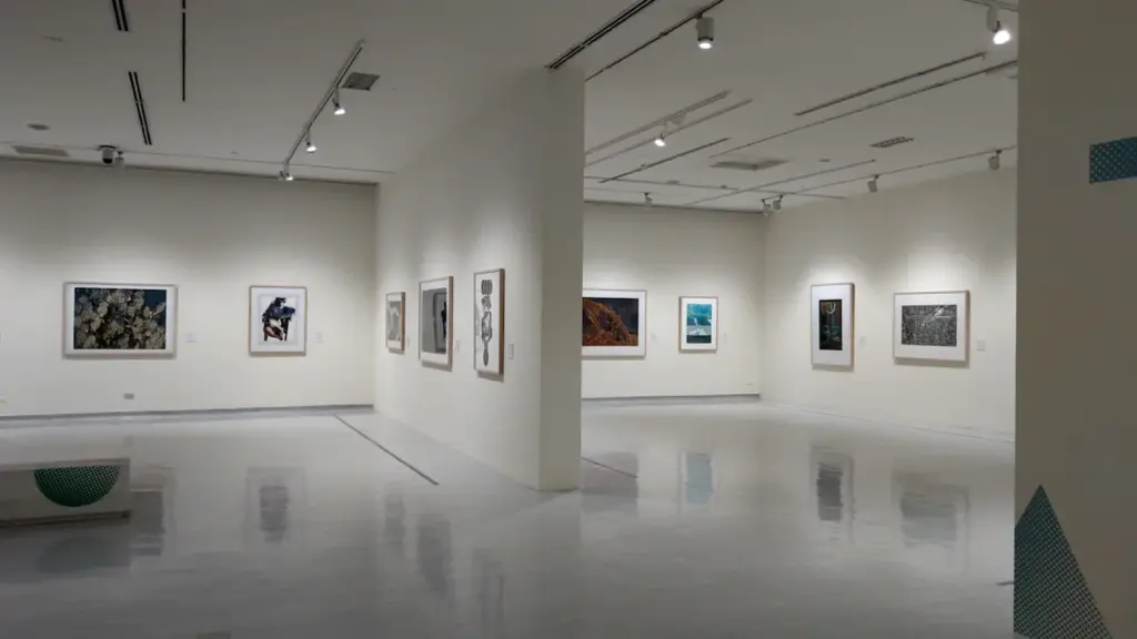 Galerie d'art moderne lumineuse présentant une exposition de peintures encadrées sur murs blancs.